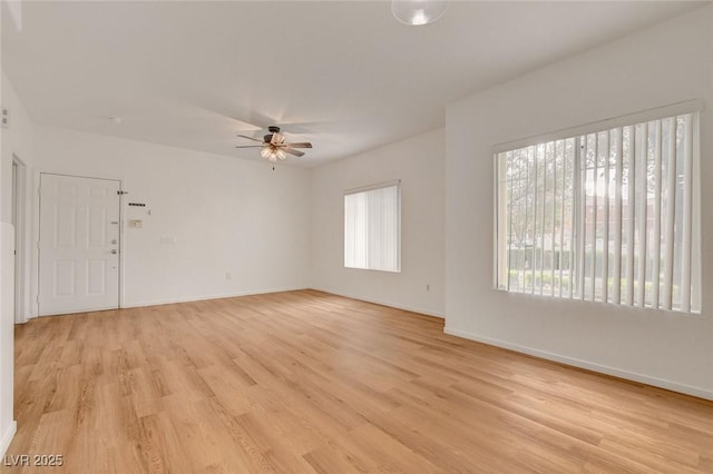 unfurnished room featuring a ceiling fan, baseboards, and light wood-type flooring