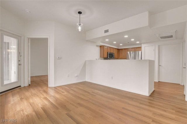 interior space with visible vents, brown cabinetry, a peninsula, light wood-type flooring, and stainless steel appliances