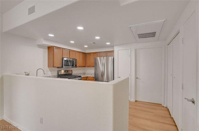 kitchen featuring a peninsula, recessed lighting, light countertops, brown cabinets, and appliances with stainless steel finishes