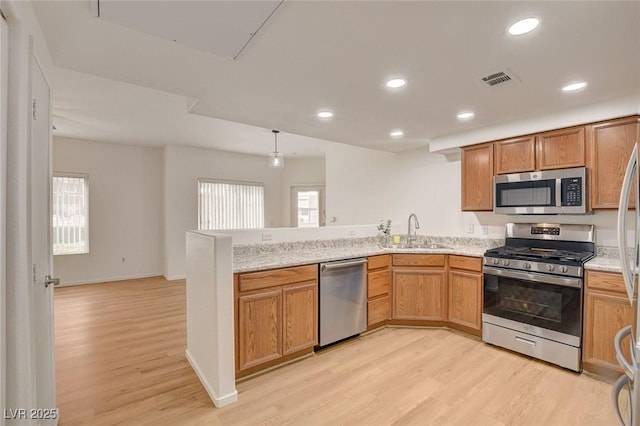 kitchen with a sink, a peninsula, light wood-style floors, stainless steel appliances, and recessed lighting