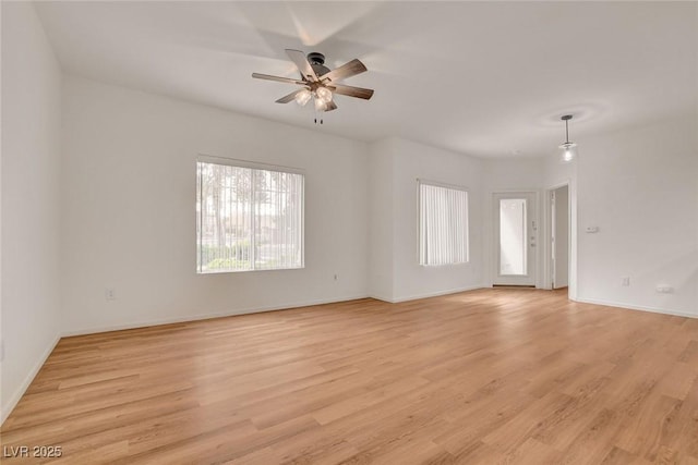 empty room featuring a ceiling fan, baseboards, and light wood-style floors