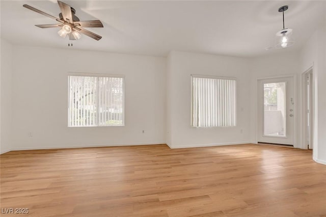 unfurnished room with ceiling fan, baseboards, and light wood-type flooring