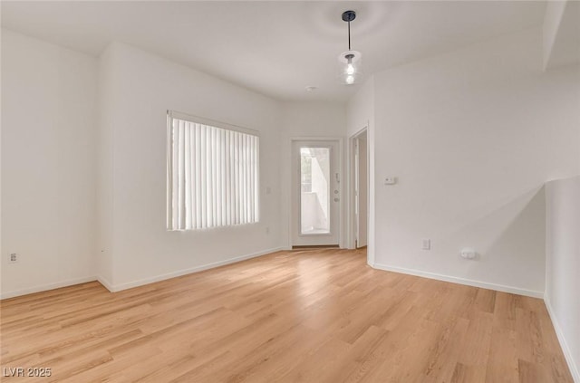 empty room featuring baseboards and light wood-style flooring