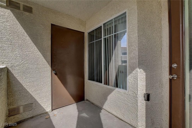 view of exterior entry featuring visible vents and stucco siding