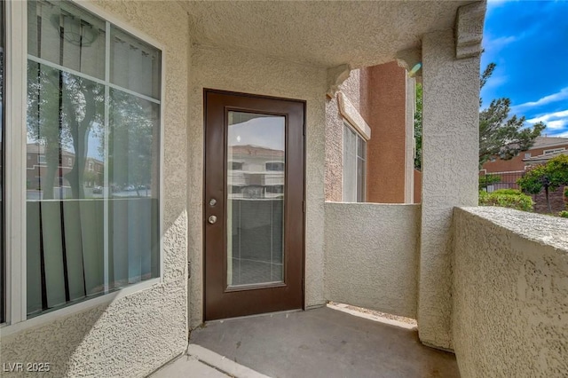 entrance to property featuring a balcony and stucco siding