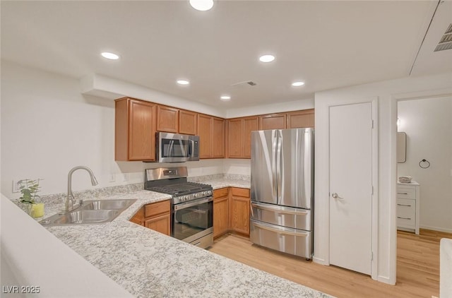 kitchen with light wood-type flooring, a sink, light countertops, stainless steel appliances, and recessed lighting