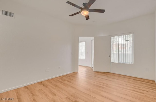 empty room featuring ceiling fan, visible vents, a wealth of natural light, and light wood-style flooring