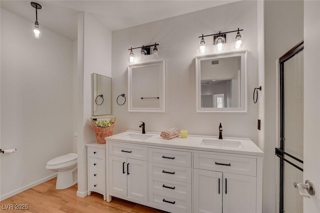full bathroom featuring double vanity, toilet, a sink, and wood finished floors