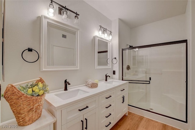 bathroom with visible vents, a shower stall, a sink, and wood finished floors