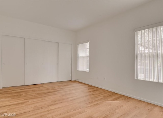 unfurnished bedroom featuring baseboards, a closet, and light wood-style flooring