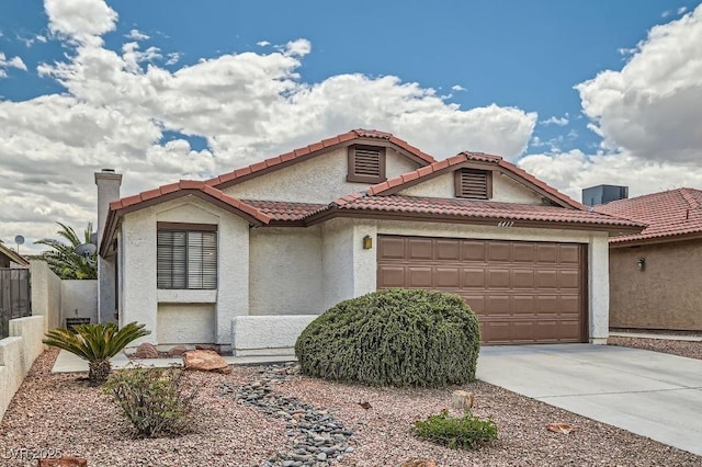 mediterranean / spanish home featuring fence, an attached garage, stucco siding, a chimney, and concrete driveway