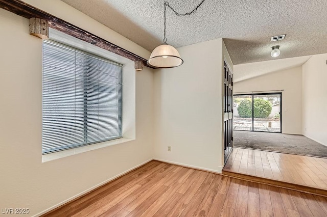 unfurnished dining area with a textured ceiling, visible vents, and hardwood / wood-style floors