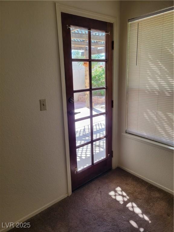 entryway featuring baseboards and dark colored carpet