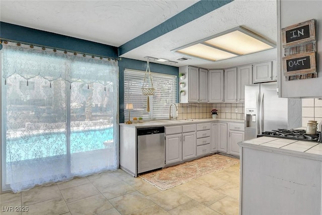 5019 Lancaster Dr, Las Vegas, NV 89120 - kitchen with appliances with stainless steel finishes, a sink, tile counters, backsplash, and gray cabinetry