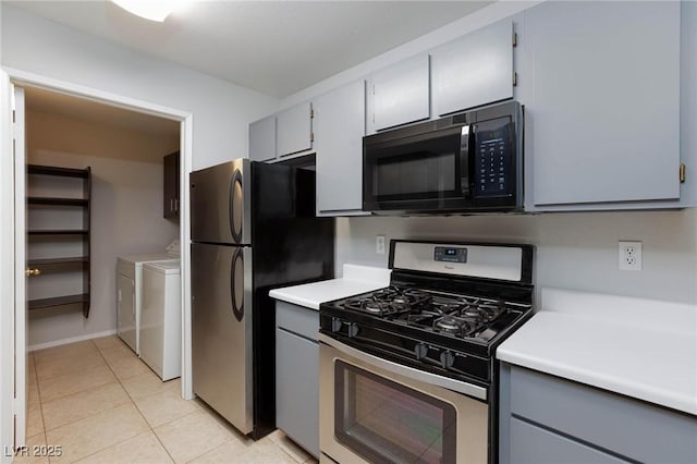 kitchen featuring light countertops, separate washer and dryer, stainless steel appliances, light tile patterned floors, and gray cabinetry