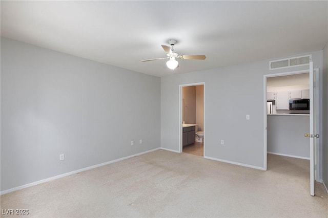 unfurnished bedroom with light carpet, baseboards, ensuite bathroom, a spacious closet, and visible vents