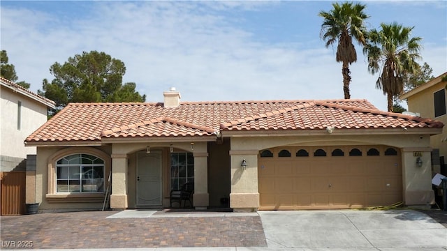 mediterranean / spanish house featuring a garage, stucco siding, a chimney, concrete driveway, and a tiled roof