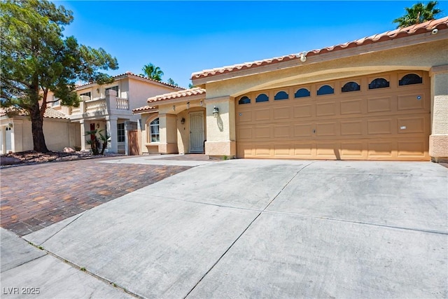 8504 W Gilmore Ave, Las Vegas, NV 89129 - mediterranean / spanish home with concrete driveway, stucco siding, a garage, a balcony, and a tile roof