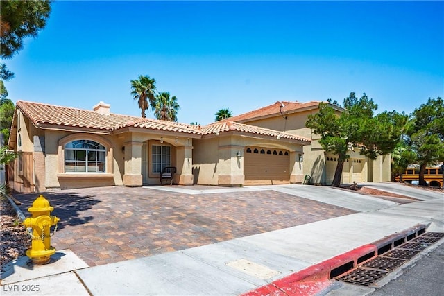 8504 W Gilmore Ave, Las Vegas, NV 89129 - mediterranean / spanish home featuring stucco siding, an attached garage, a tiled roof, and driveway