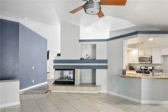 8504 W Gilmore Ave, Las Vegas, NV 89129 - living room with a ceiling fan, light tile patterned floors, baseboards, and a multi sided fireplace