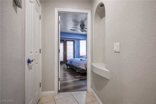 8504 W Gilmore Ave, Las Vegas, NV 89129 - hallway featuring light tile patterned floors, baseboards, a textured wall, and french doors
