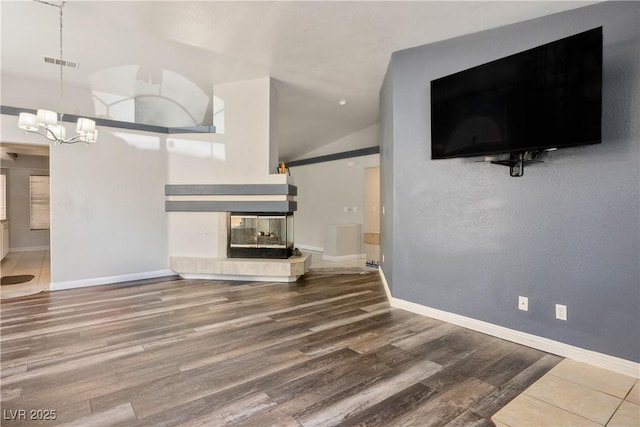 8504 W Gilmore Ave, Las Vegas, NV 89129 - unfurnished living room with vaulted ceiling, a chandelier, wood finished floors, a fireplace, and baseboards