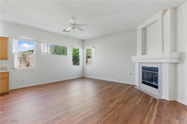 unfurnished living room featuring ceiling fan, visible vents, light wood-style flooring, and a tile fireplace