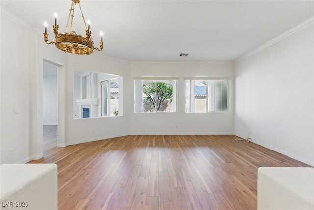 empty room with crown molding, an inviting chandelier, light wood-style flooring, and visible vents