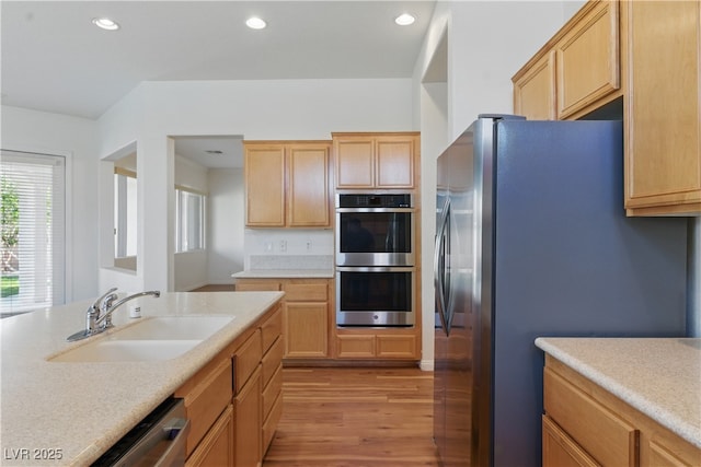 kitchen with recessed lighting, light countertops, a sink, light wood-style flooring, and stainless steel appliances