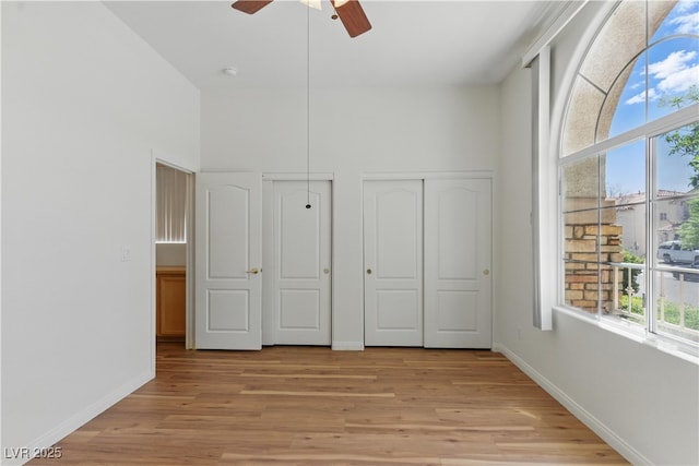 unfurnished bedroom featuring a ceiling fan, baseboards, and light wood-type flooring