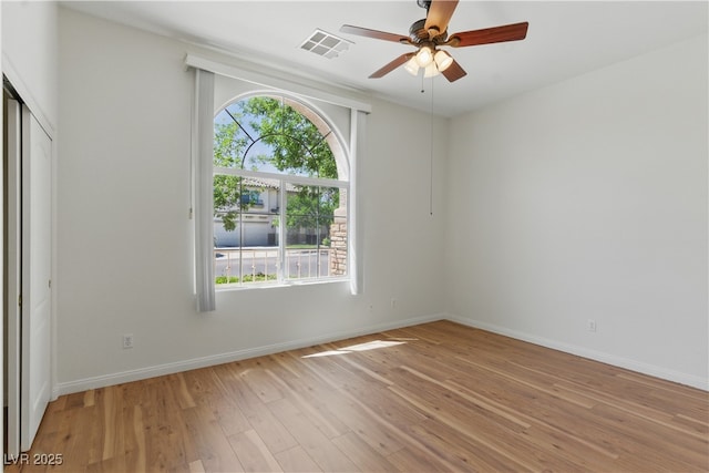 empty room with a ceiling fan, visible vents, a wealth of natural light, and light wood finished floors
