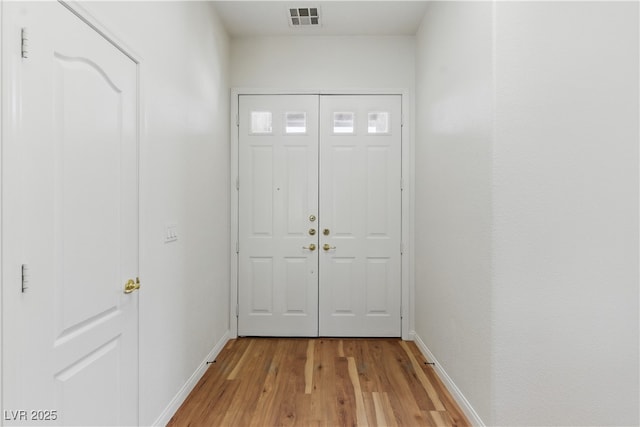 doorway featuring baseboards, light wood-style floors, and visible vents