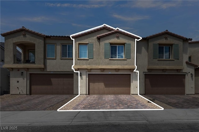 multi unit property featuring an attached garage, stucco siding, and driveway