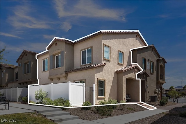 mediterranean / spanish home featuring fence, a tiled roof, and stucco siding