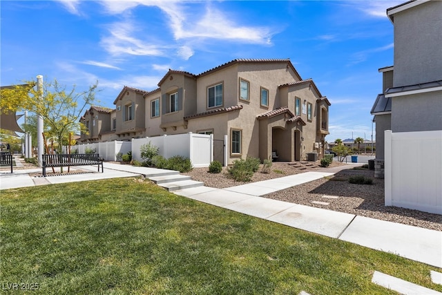 view of front of home with a tiled roof, a residential view, fence, a front lawn, and stucco siding