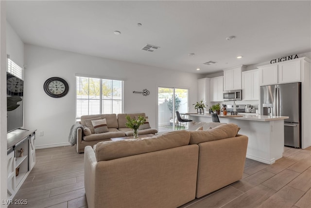 living area with visible vents, recessed lighting, and light wood-style flooring