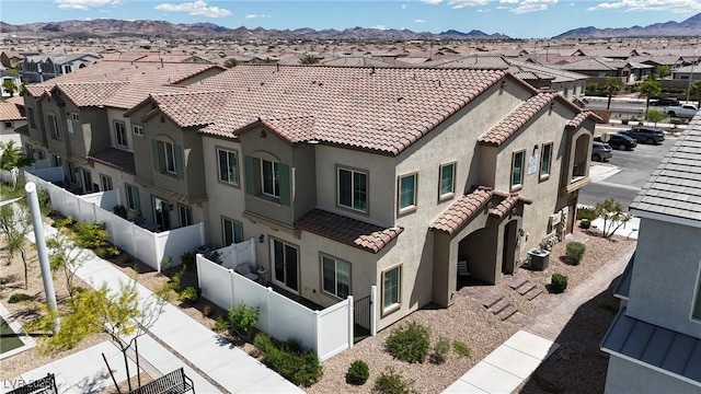 view of building exterior with a mountain view, a residential view, fence private yard, and central AC unit