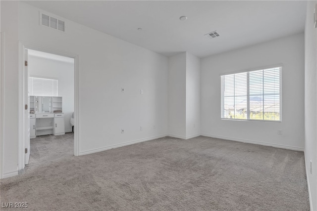 carpeted spare room featuring baseboards and visible vents