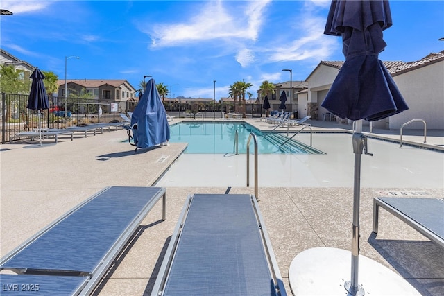 pool with a patio, fence, and a residential view