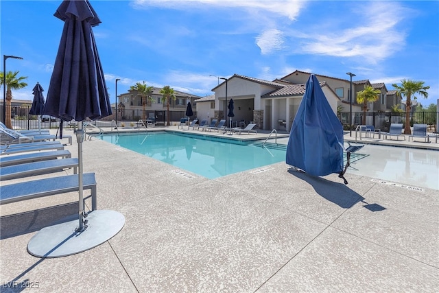 community pool featuring fence, a patio, and a residential view