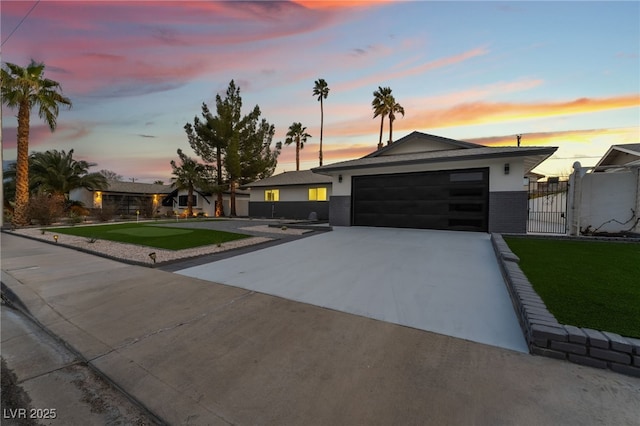 contemporary house featuring a garage, a gate, stucco siding, and driveway