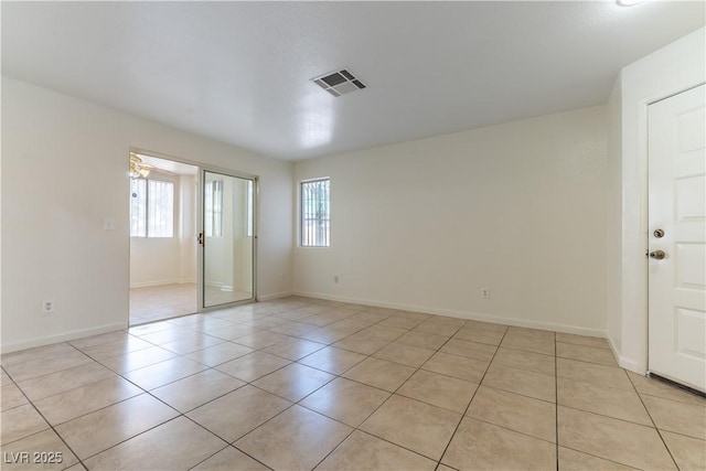 unfurnished room featuring light tile patterned floors, baseboards, visible vents, and a wealth of natural light