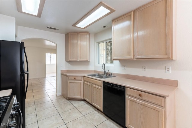kitchen featuring visible vents, a sink, light brown cabinetry, arched walkways, and black appliances