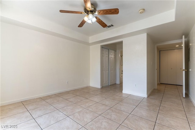 empty room featuring light tile patterned floors, baseboards, ceiling fan, and visible vents