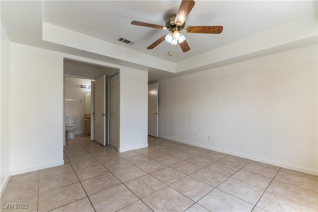 spare room with light tile patterned flooring, a ceiling fan, visible vents, and a tray ceiling