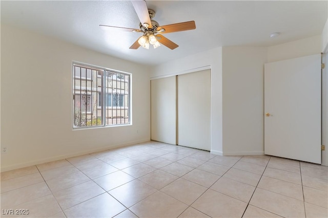 unfurnished bedroom with baseboards, ceiling fan, light tile patterned floors, and a closet