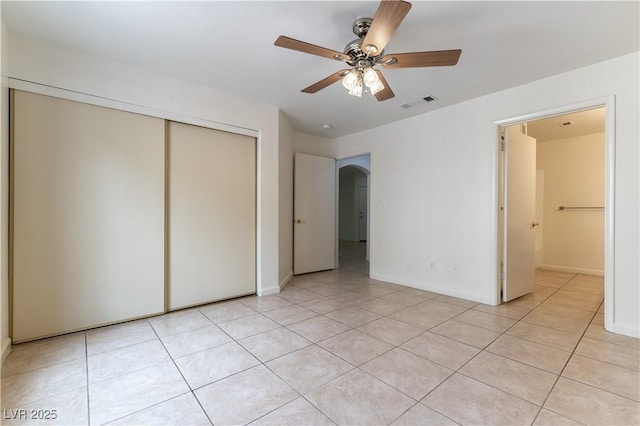 unfurnished bedroom with visible vents, a closet, baseboards, arched walkways, and light tile patterned floors