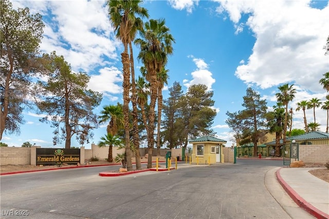 view of road featuring curbs, sidewalks, and a gate