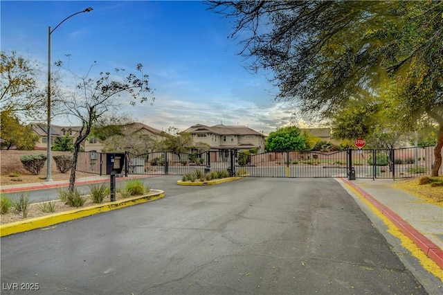 view of road with a gate, a gated entry, curbs, and sidewalks