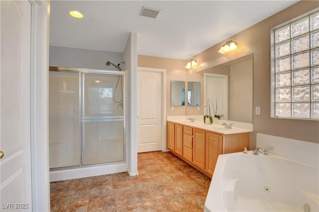 full bathroom featuring visible vents, a sink, a stall shower, and a jetted tub